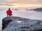 Man hiker at mountain peak. Marvelous daybreak in autumn misty landscape. Sun hidden in clouds