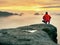 Man hiker at mountain peak. Marvelous daybreak in autumn misty landscape. Sun hidden in clouds