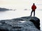 Man hiker at mountain peak. Marvelous daybreak in autumn misty landscape. Sun hidden in clouds