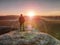 Man hiker at mountain peak. Nice daybreak in misty landscape