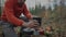 Man hiker sets up system for cooking while camping in woods. Traveler prepares to cook food on burner. Eating and