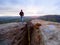 Man hiker on sharp cliff. Hiker climbed up to peak enjoy view. Man watch over morning valley