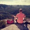 Man hiker sitting on the top of the mountain in yoga pose