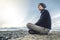 Man hiker sitting in a yoga pose at the peak of the mountain in the summer. Meditation after a long climb on a mountain