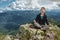 Man hiker sitting in a yoga pose at the peak of the mountain in the summer. Meditation after a long climb on a mountain