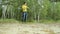 Man hiker walking through the forest and touch smart watch. Yellow T-shirt and jeans with suspenders. Technology in the