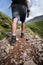 Man hiker walking on mountain rocks with sticks. Beautiful weather with Scotland nature. Detail of hiking boots on the difficult p