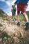 Man hiker walking on mountain rocks with sticks. Beautiful weather with Scotland nature. Detail of hiking boots on the difficult p