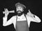 Man or hipster with beard holds macaroni on black background. Chef with spaghetti shows thumbs up. Cooking italian food
