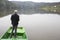 Man With His Back Towards Camera Fishing From The Boat Reeling String And Waiting Fish To Take A Bait Water Reflection