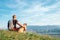 Man with his beagle dog sits on the top of hill over the mountain valley