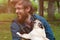 Man with his dog playing outdoor in the park. Young owner hugs his pet, dog lick nose her owner