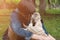 Man with his dog playing outdoor in the park. Young owner hugs his pet, dog lick nose her owner