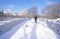 Man and his dog walk with Red Sweater over arch bridge in fresh snow in Central Park, Manhattan, NY