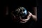 A man in his hands holds a mockup of the planet earth on a black background, the concept of saving ecology on the planet