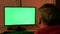 A man in his home office, in front of a green computer screen. Work at home.