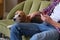 Man and his loyal Beagle spending a lazy afternoon on the sofa: browsing social media and petting his furry companion