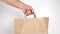 Man hold in hand craft paper bag for give takeaway