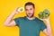 Man hold vegetables, isolated on yellow. Man holding avocado and broccoli vegetables. Cooking vegetables. Dieting, bowl