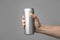 Man holding aluminum can with beverage on grey background, closeup.