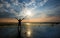 Man holding arms up in praise in sunset while being in water