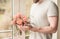 Man holding a beautiful festive bouquet on his outstretched arms against the background of the window and leaves of plants