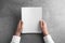 Man holding blank booklet at grey table. Mock up for design