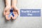 Man holding blue ribbon on background, top view. World Cancer Day