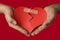 Man holding a broken heart glued on a red background
