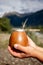 Man holding calabash yerba mate in nature. Travel and adventure concept. Latin American drink yerba mate