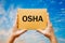 Man holding a card with text OSHA - Occupational Safety and Health Administration