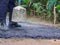 Man holding a cement rod for hammering to adjust the asphalt surface for the walkway. Close-up photo. Constructed from asphalt.