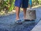 Man holding a cement rod for hammering to adjust the asphalt surface for the walkway. Close-up photo. Constructed from asphalt.