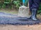 Man holding a cement rod for hammering to adjust the asphalt surface for the walkway. Close-up photo. Constructed from asphalt.