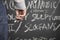 Man Holding Chalk In Front Of Blackboard