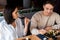 Man holding chopsticks near sushi while woman drinking wine