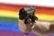 Man holding close up gun with background gay parade flag representing sexual discrimination