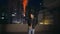 Man holding colorful flare at night cityscape framing urgent signal. Latino guy