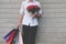 Man holding colorful shopping bag & red rose bouquet outdoors. s