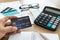 Man holding credit card with calculator , glasses , credit cards and bill on the table, account and saving concept