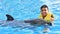 Man holding dolphin in pool