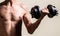 Man holding dumbbell in hand. Skinny guy hold dumbbells up in hands. A thin man in sports with dumbbells. Weak man lift