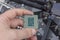 Man holding fingers desktop processor 8th gen on background motherboard closeup