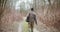 Man holding fishing rod walking amidst bare trees