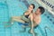 Man holding floats for pregnant woman to sit on in pool