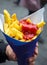 Man holding French fries in paper cornet with ketchup. Street food