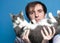 Man holding in front of face lying on back cute gray and white cat and looking at camera on blue background