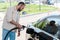 Man holding fuel pump and refueling black car at gas station