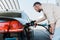 Man holding fuel pump and refueling black car at gas station