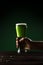 Man holding glass of green beer above table with coins, st patricks day concept